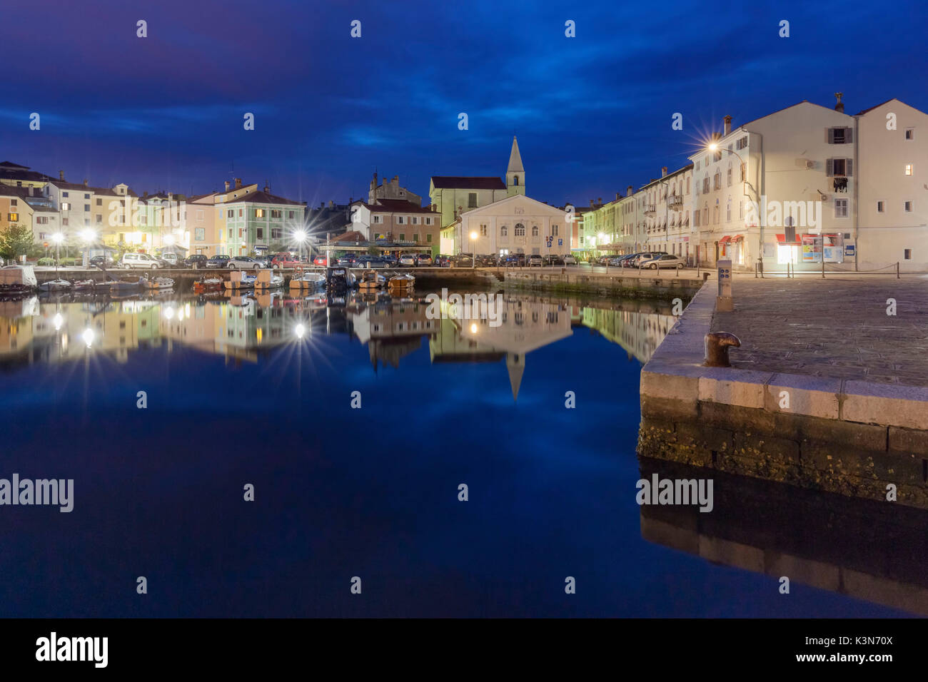 Europe, Slovenia, Primorska, Izola. Old town and the harbour with fishing boats at night Stock Photo