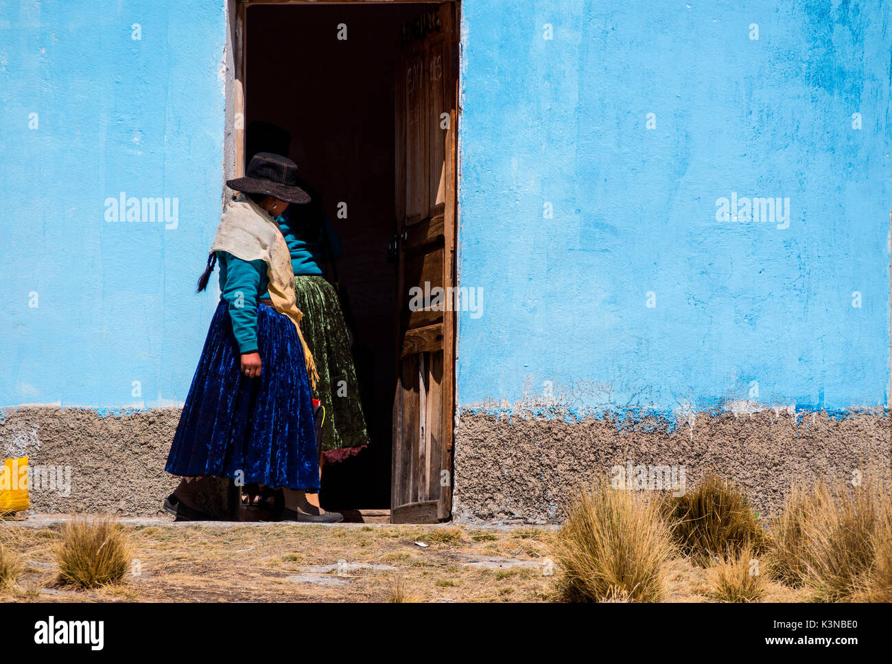 Young Ayamara women in the typical costume just outside her colored house. Aymaras are the native population of the Titicaca Lake area, in Bolivia, South America. Stock Photo