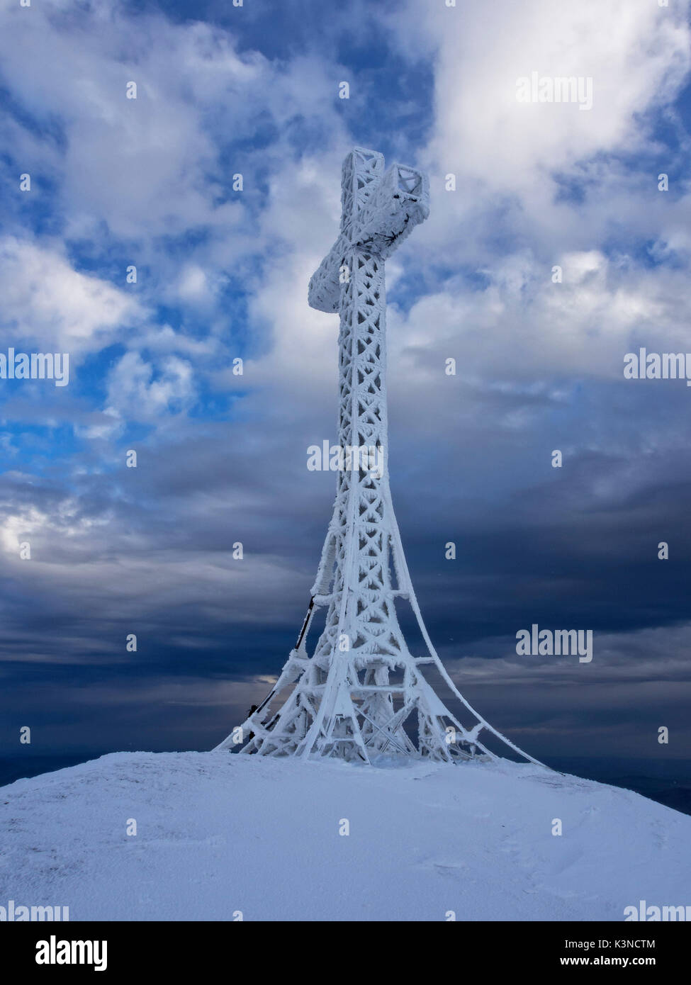 Frozen summit cross of mount Catria in winter at sunset, mount Catria, Marche, Italy Stock Photo