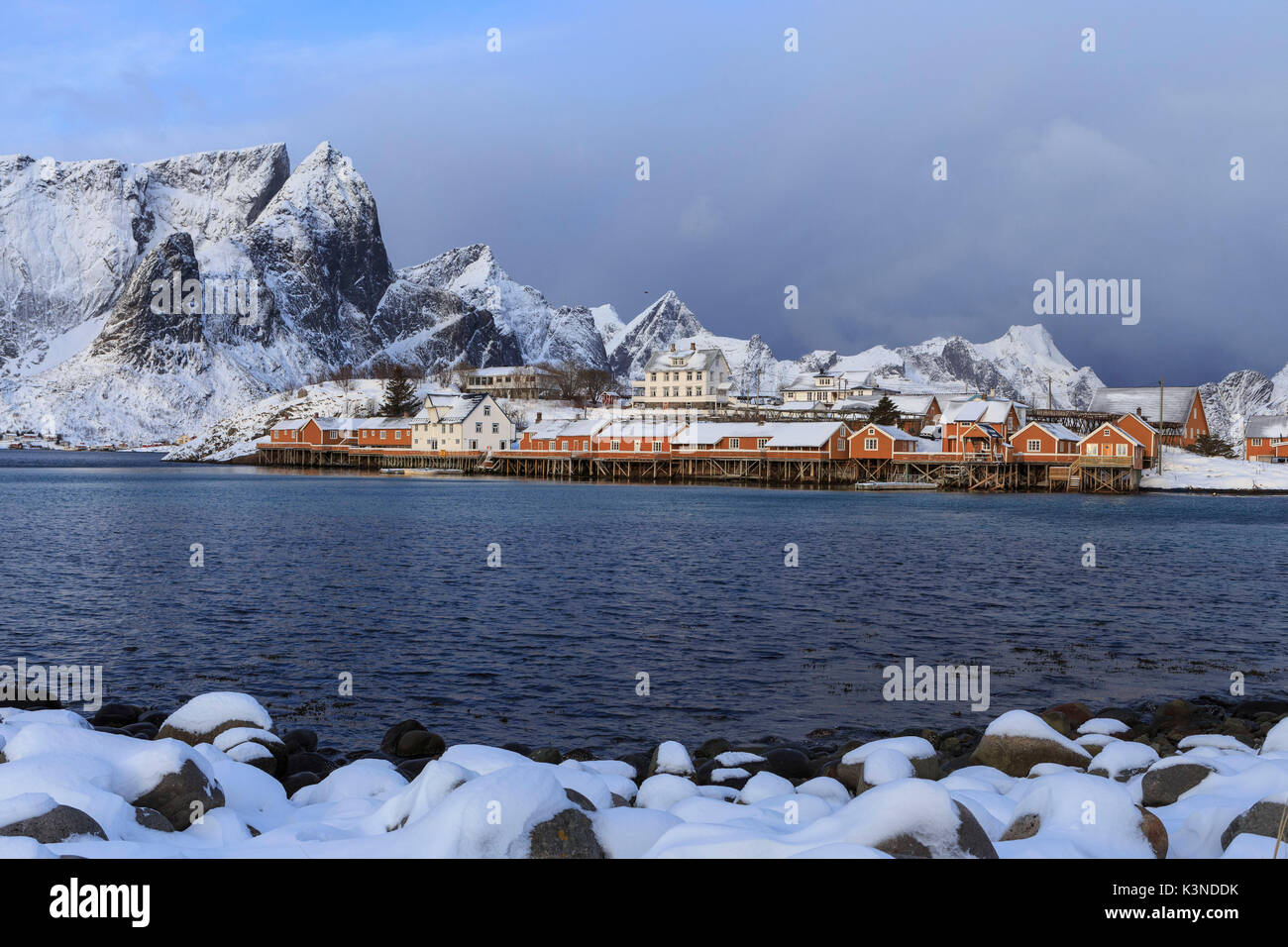 Stilt houses against the jagged mountain tops and overcast sky, Moskenes,  Lofoten Islands, Norway Stock Photo