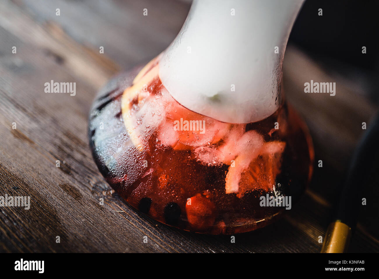 sweaty hookah fruit flask with smoke on a wooden table Stock Photo