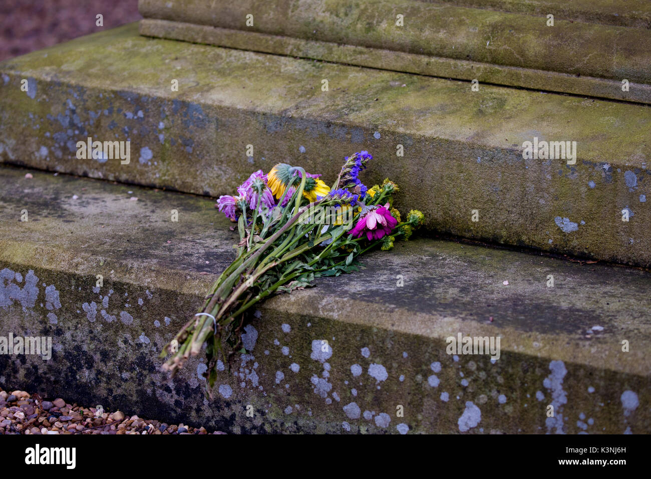 A bunch of flowers placed at the base of a war memorial Stock Photo - Alamy