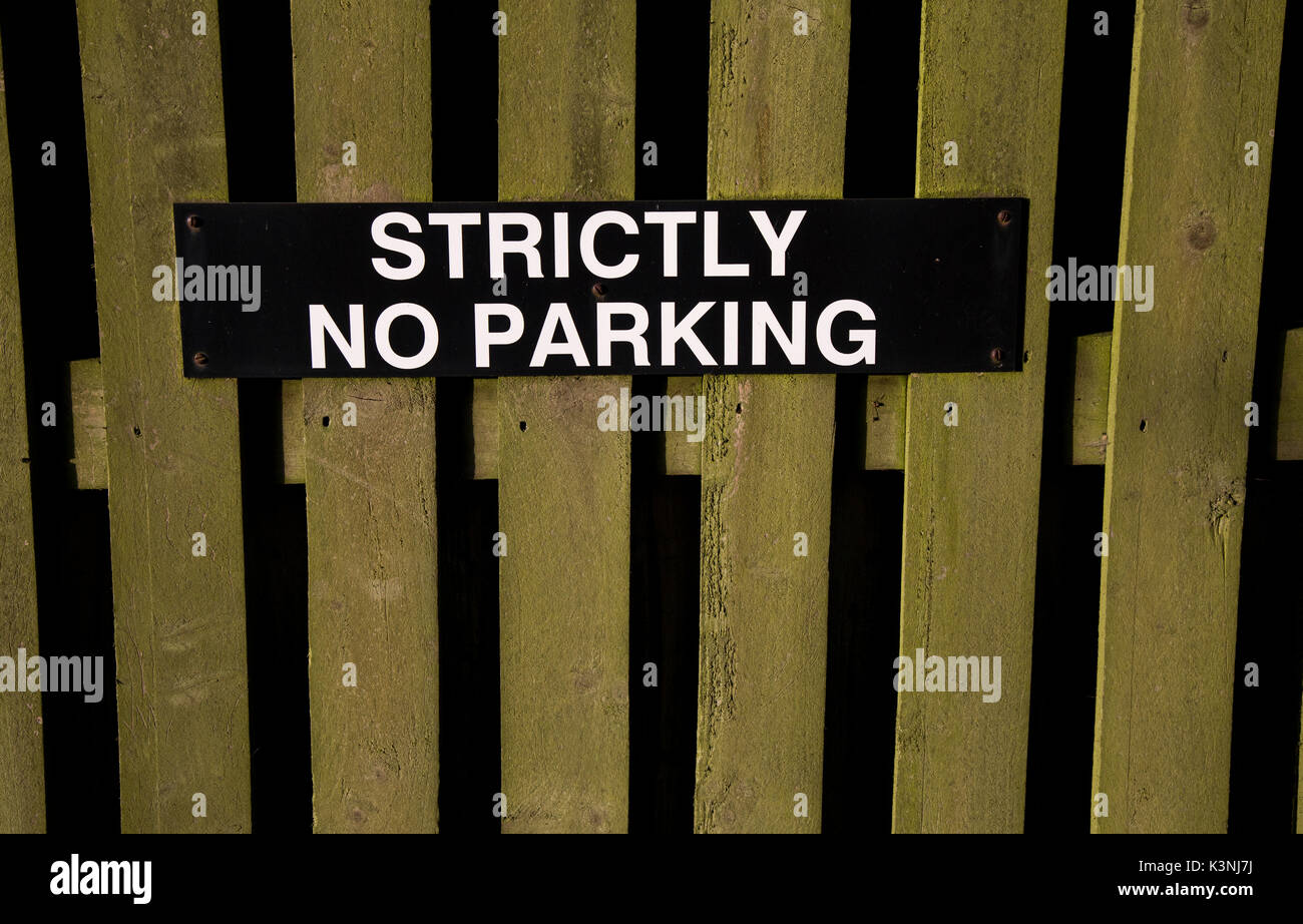 A "Strictly No Parking" sign is attached to a wooden fence Stock Photo