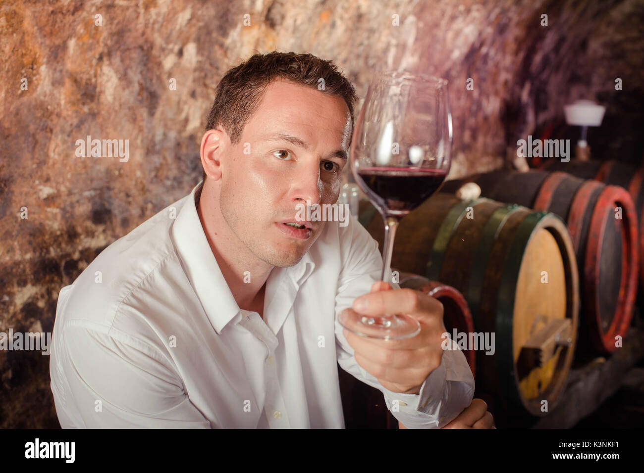 man having wine tasting in cellar Stock Photo
