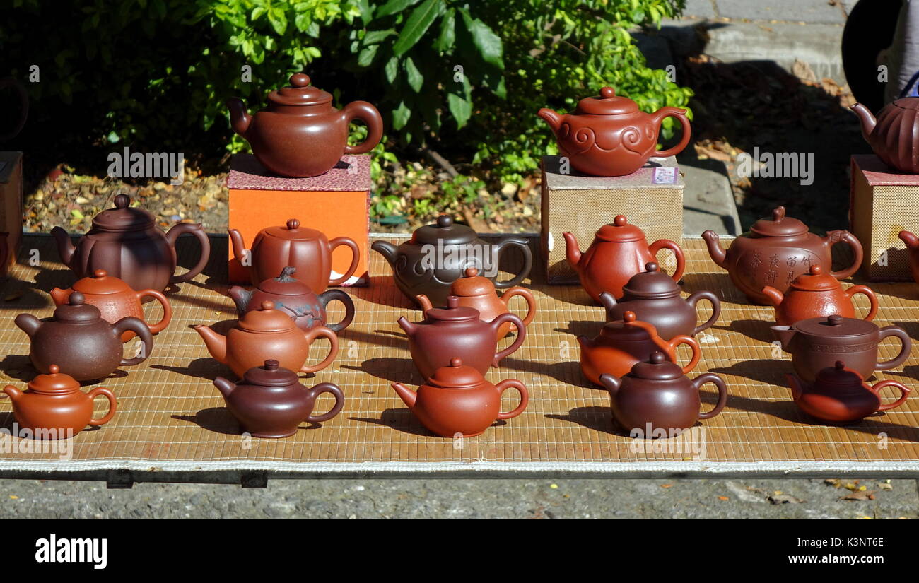 An outdoor vendor sells teapots made from characteristic red clay Stock