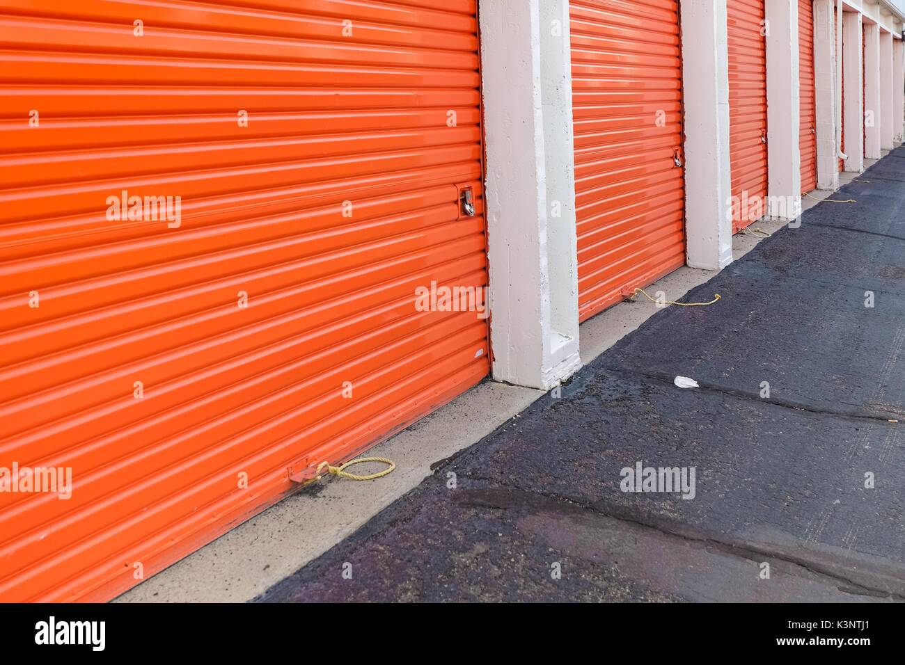 Row of an orange metal doors of a public storage, perspective Stock