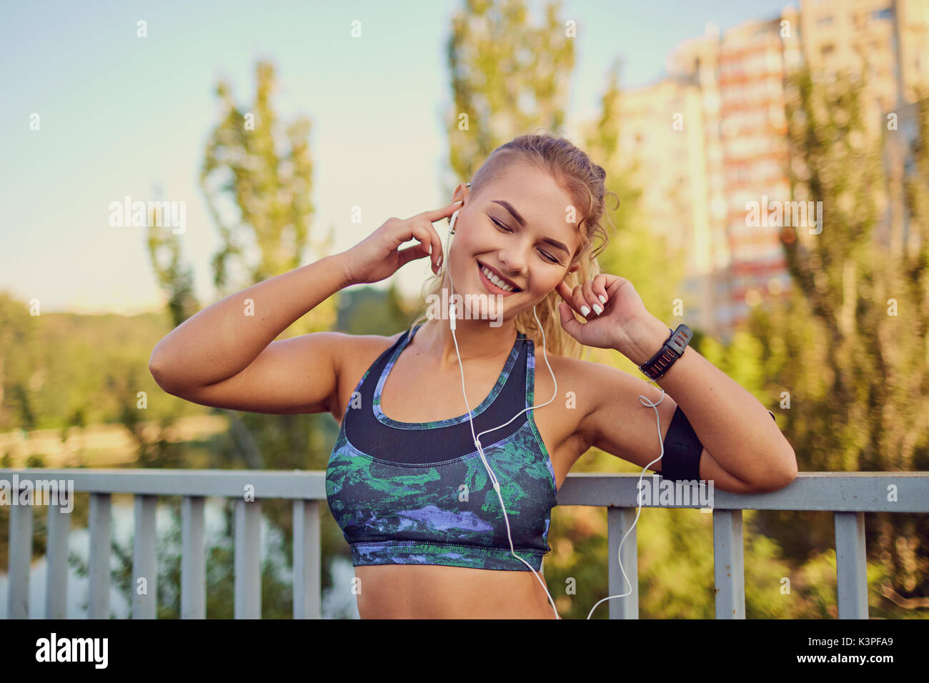 A happy girl jogger listens to music on headphones on a park. Stock Photo