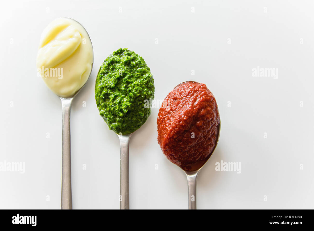 Three spoons with different condiments mayonnaise, tomato sauce and pesto Stock Photo Alamy