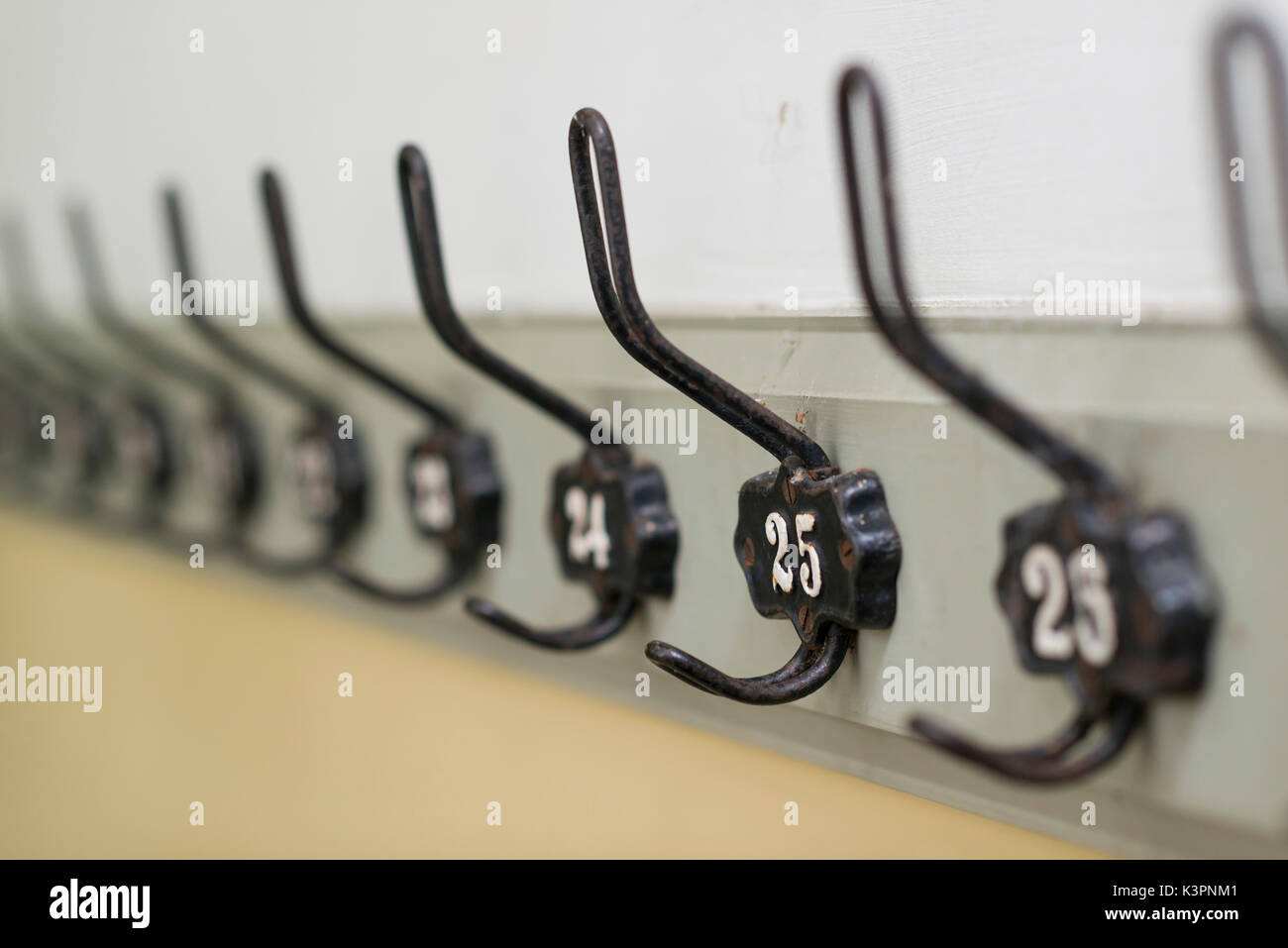Old fashioned authentic coat hooks in a row on a wall of a dutch school Stock Photo