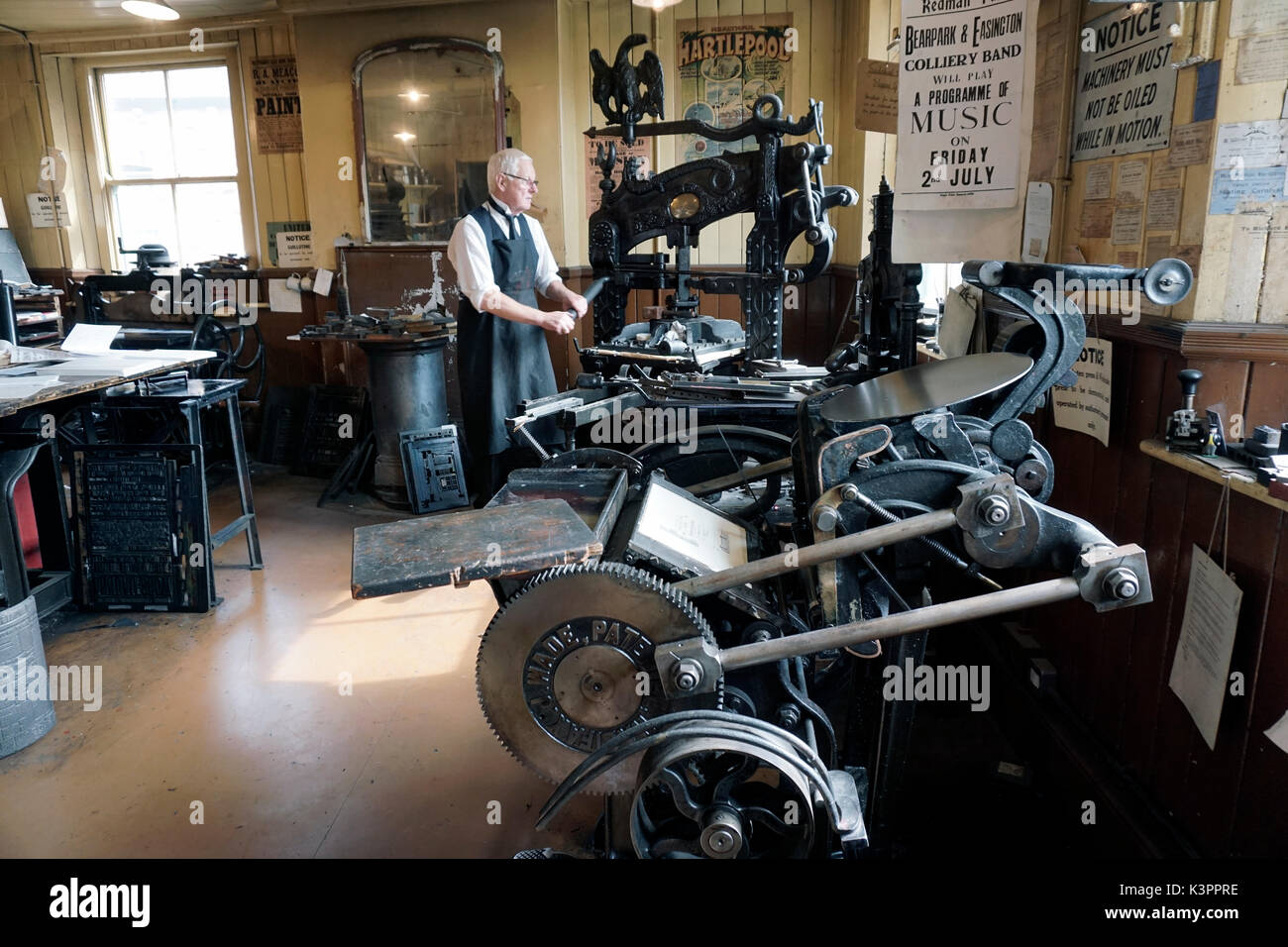 older male printer working vintage flatbed printing press surrounded by  vintage printing platen press Stock Photo - Alamy