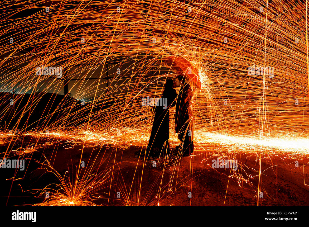 Couple under an umbrella to shelter from a shower of incandescent sparks created by the technique of steel wool, emilia romagna, italy Stock Photo