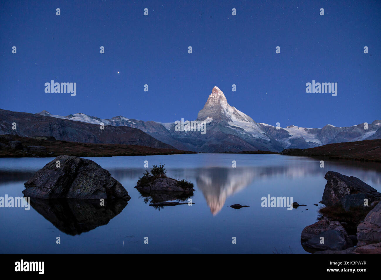 The Matterhorn colossus reflecting in the still water of Lake Stellisee in a clear night. This mirror is just one of the many little lakes spotting the Zermatt heights, famous Swiss resort - Zermatt, Canton of Valais, Switzerland. Europe Stock Photo