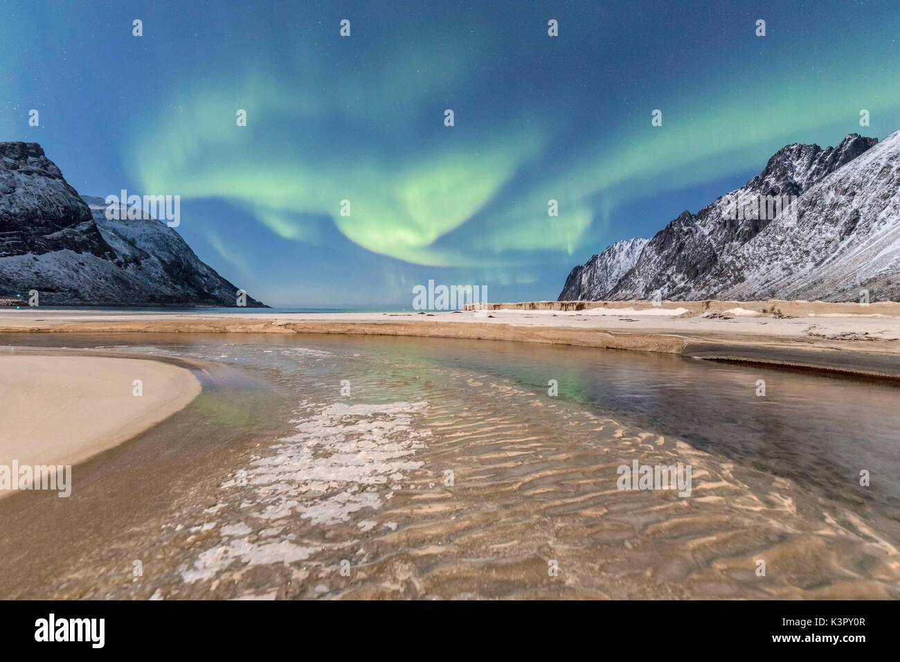 Green lights of Aurora Borealis reflected in the cold sea surrounded by snowy peaks Ersfjord Senja Tromsø Norway Europe Stock Photo