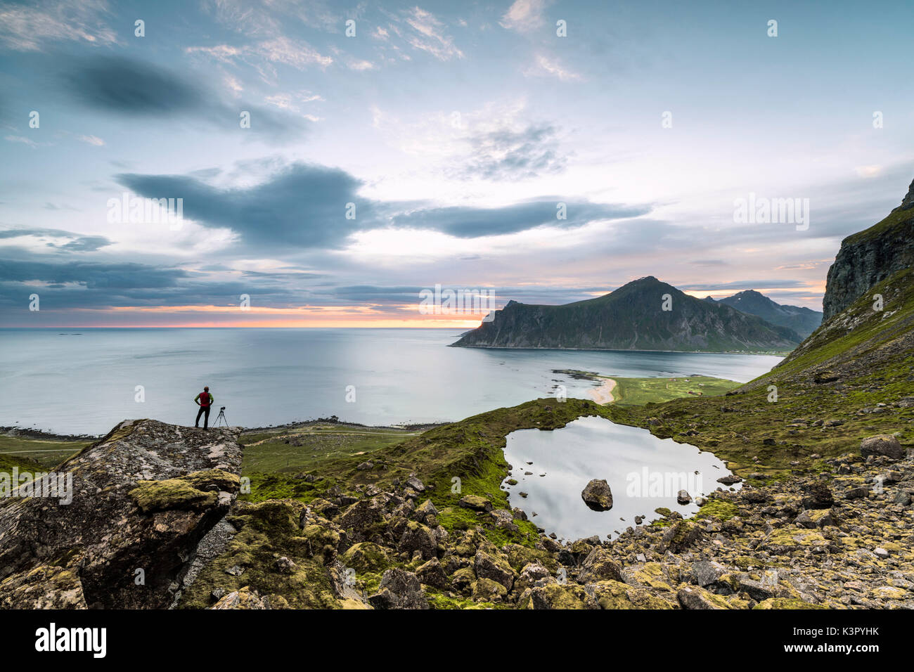 Photographer admires clouds of midnight sun on the cold sea Flakstad Moskenesøya Nordland county Lofoten Islands Norway Europe Stock Photo