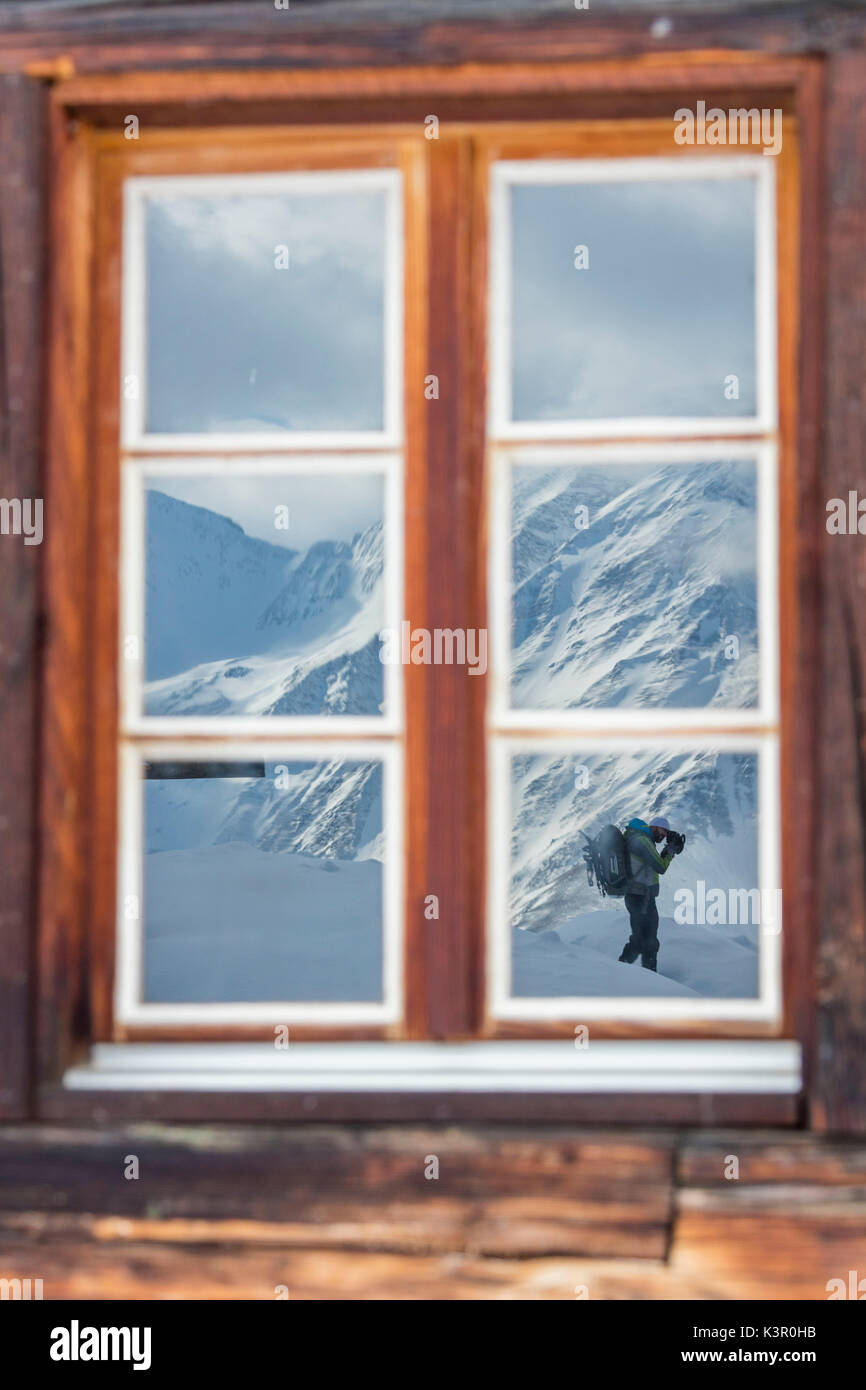 The photographer is reflected by window of the wooden hut Bettmeralp district of Raron canton of Valais Switzerland Europe Stock Photo