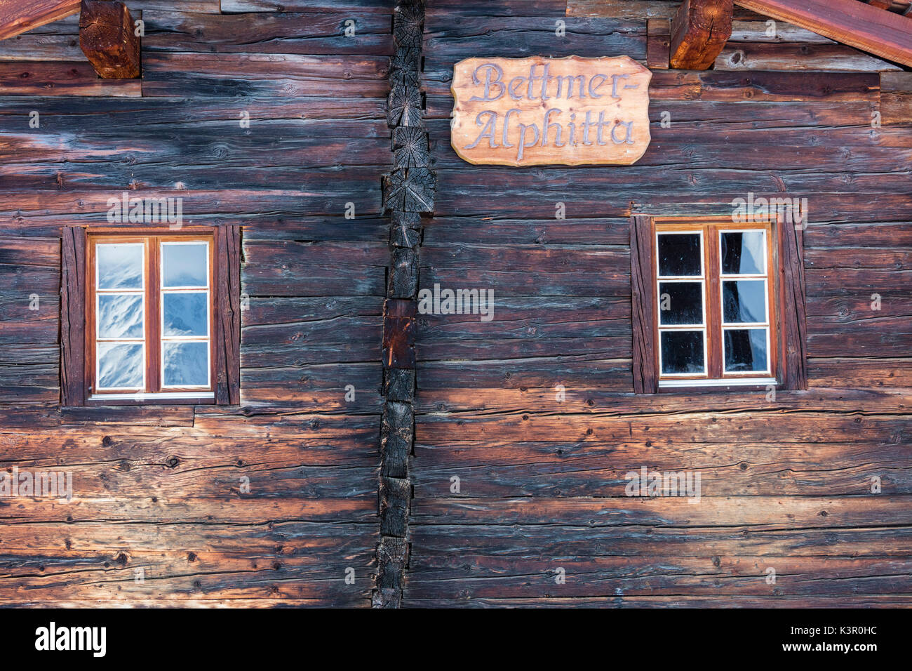 Snowy peaks are reflected into the windows of the wooden hut Bettmeralp district of Raron canton of Valais Switzerland Europe Stock Photo