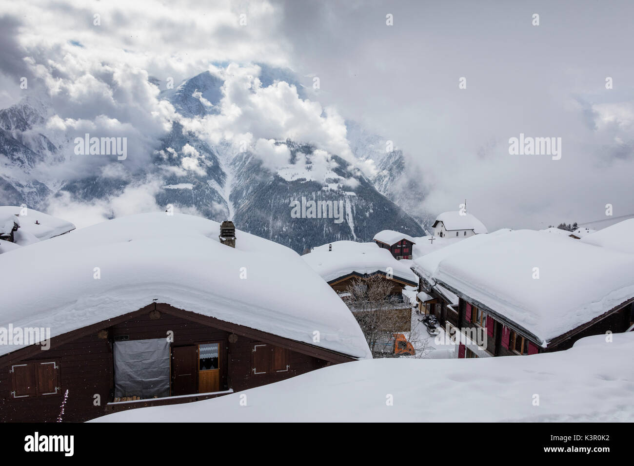 Clouds frame the mountain huts covered with snow Bettmeralp district of Raron canton of Valais Switzerland Europe Stock Photo