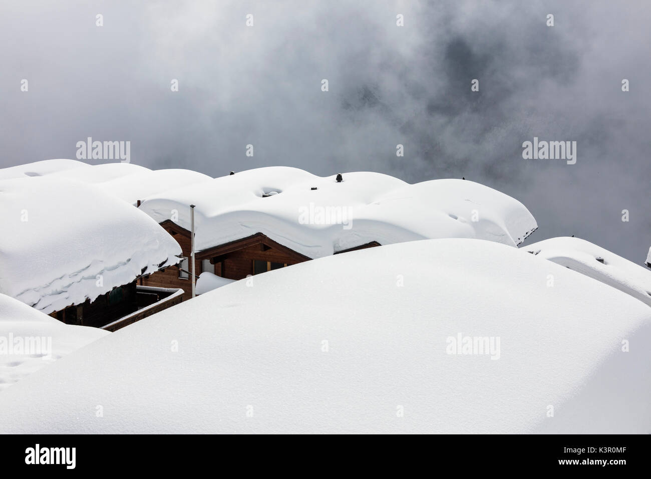 Snow covered mountain huts surrounded by low clouds Bettmeralp district of Raron canton of Valais Switzerland Europe Stock Photo