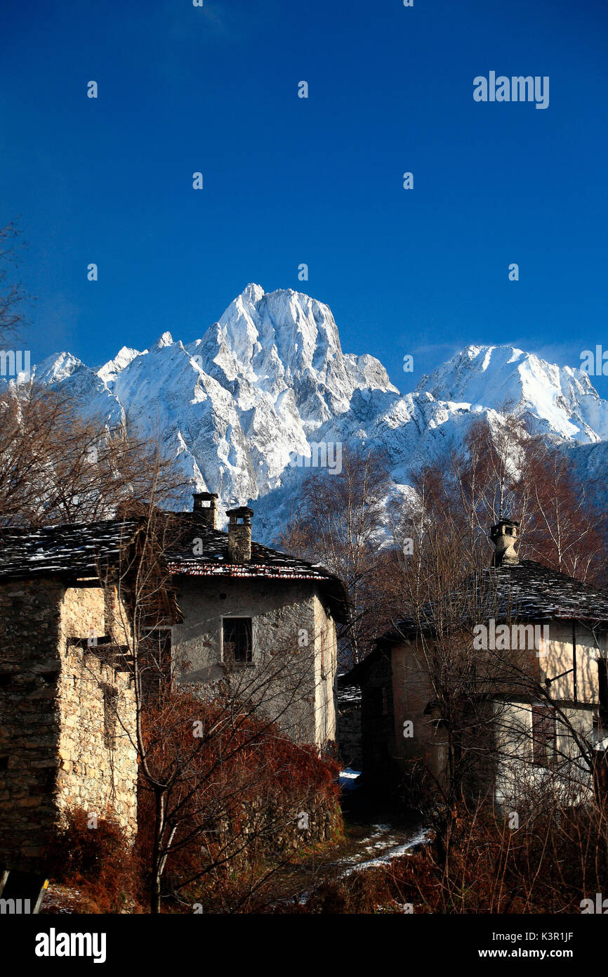 The top of Sasso Manduino whitened by heavy snowfall dominates the old houses of Dascio village. Sorico. High Lario. Como lake. Valchiavenna. Valtellina. Lombardy. Italy. Europe Stock Photo