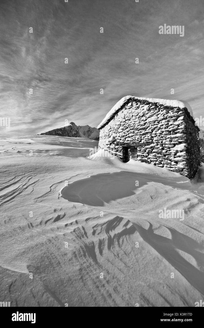 Black and white photograph depicting a cabin of Olano Alp whitewashed by a snow storm. Rasura. Valgerola. Alps Orobie. Valtellina. Lombardy. Italy. Europe Stock Photo