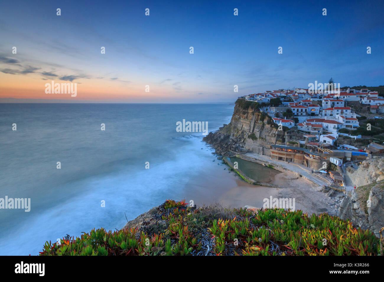 The soft colors of twilight frame the ocean and the village of Azenhas do Mar Sintra Portugal Europe Stock Photo
