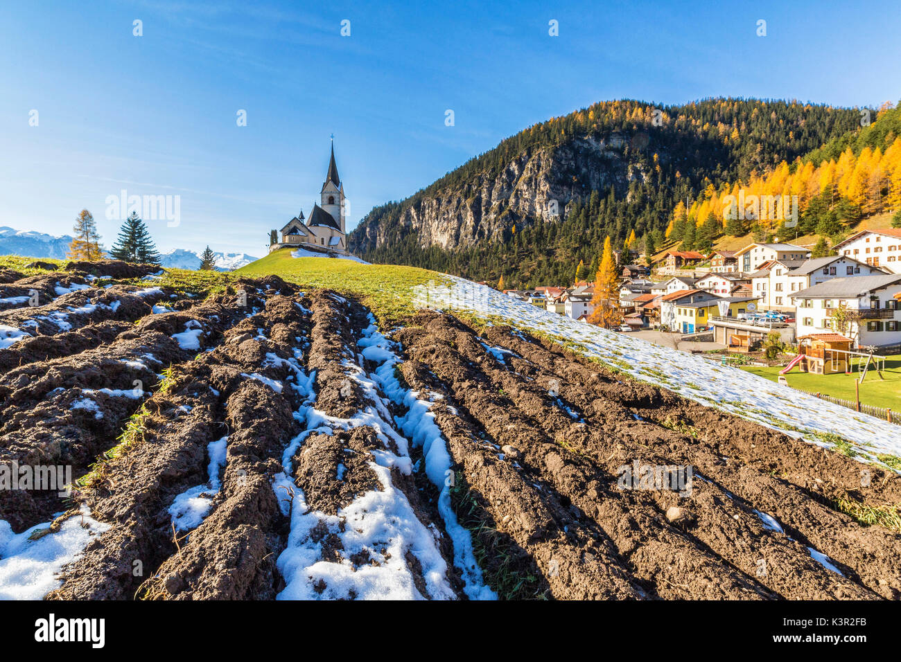 The church of Schmitten surrounded by colorful woods and snow Albula District Canton of Graubünden Switzerland Europe Stock Photo