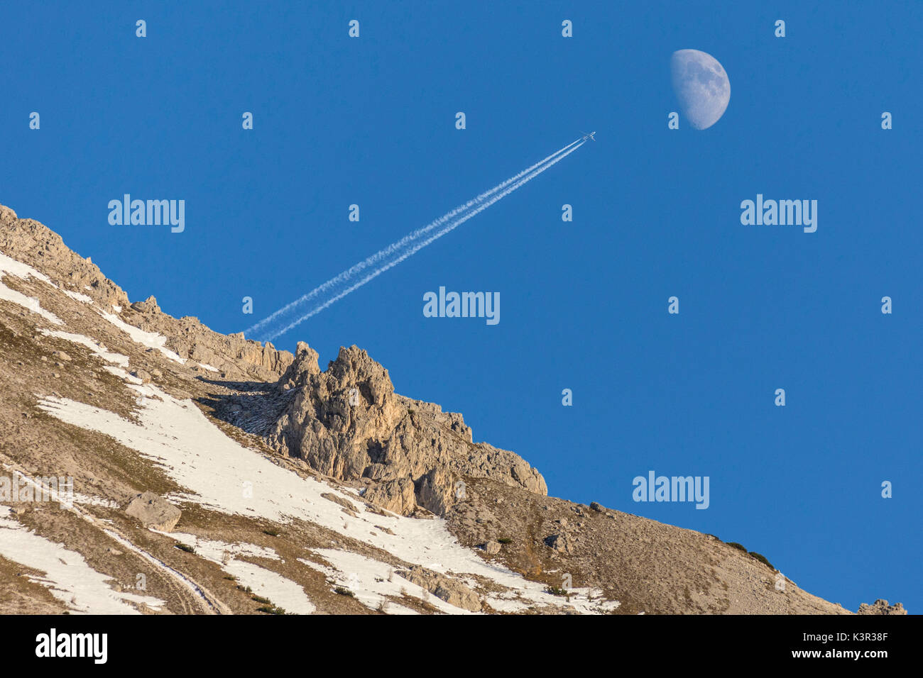The plane and the moon in the blue sky of Dolomites Auronzo of Cadore Veneto Italy Europe Stock Photo