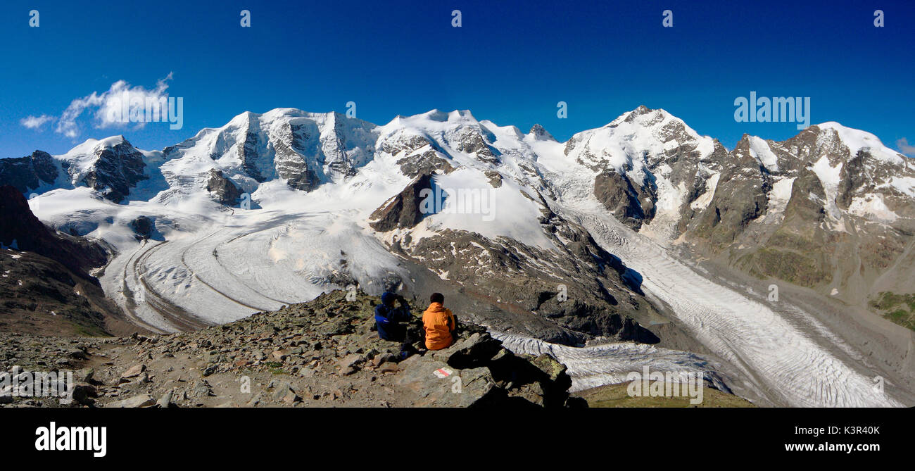 Hikers looking at the vastness of the glaciers of Bernina from Diavolezza Refuge. Engadine, Canton of Graubunden, Switzerland Europe Stock Photo