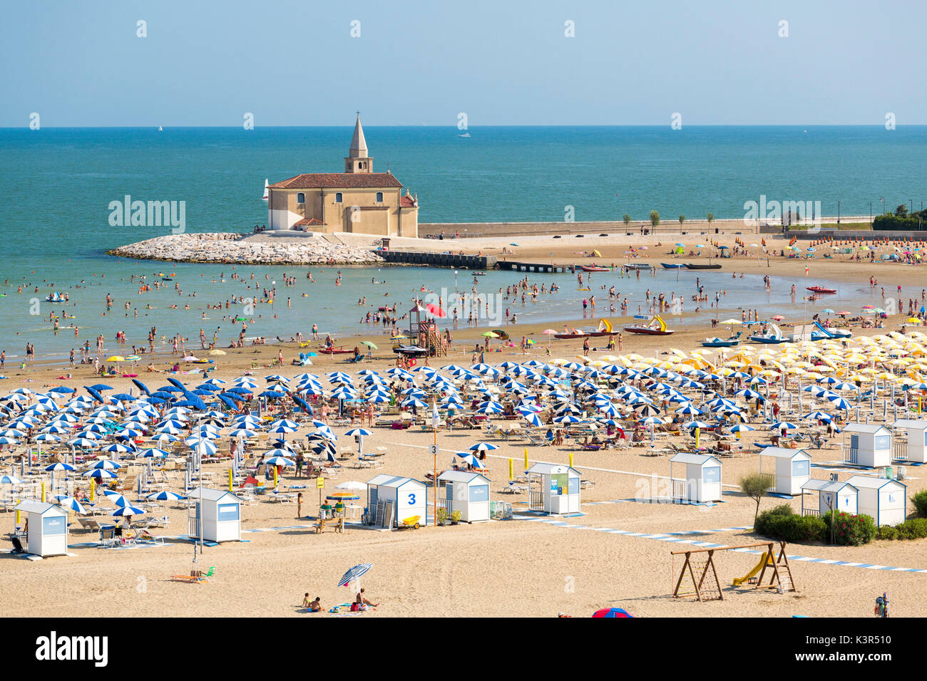 Sun umbrellas on the sand beach overlooking the Sanctuary of Madonna ...