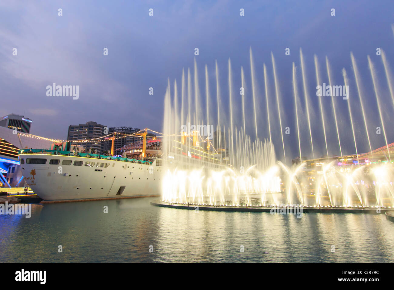 Dancing Fountains in New Sea World Plaza, one of the landmark of Shenzhen, at sunset with the Minghua ship on its center. The ship was originally known as Anceevilla and  was later renamed 'Minghua' by the chinese who bought it, China Stock Photo