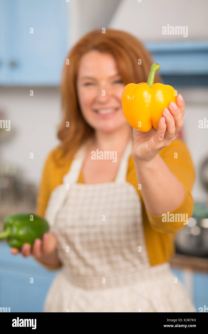 Close up view of yellow pepper in hand of attractive housewife. Stock Photo