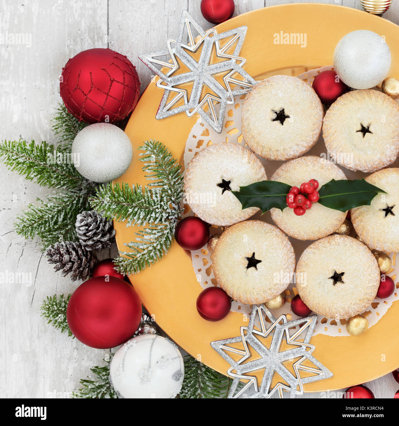 Christmas mince pies on a gold plate with holly, fir, bauble ...