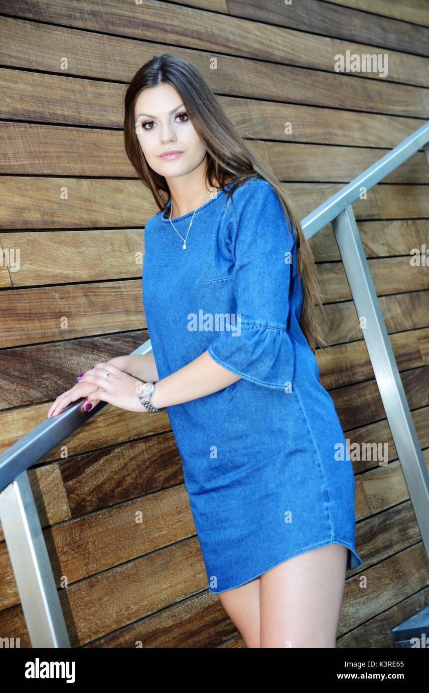 Young female model wearing blue jeans dress. Girl posing in Wroclaw