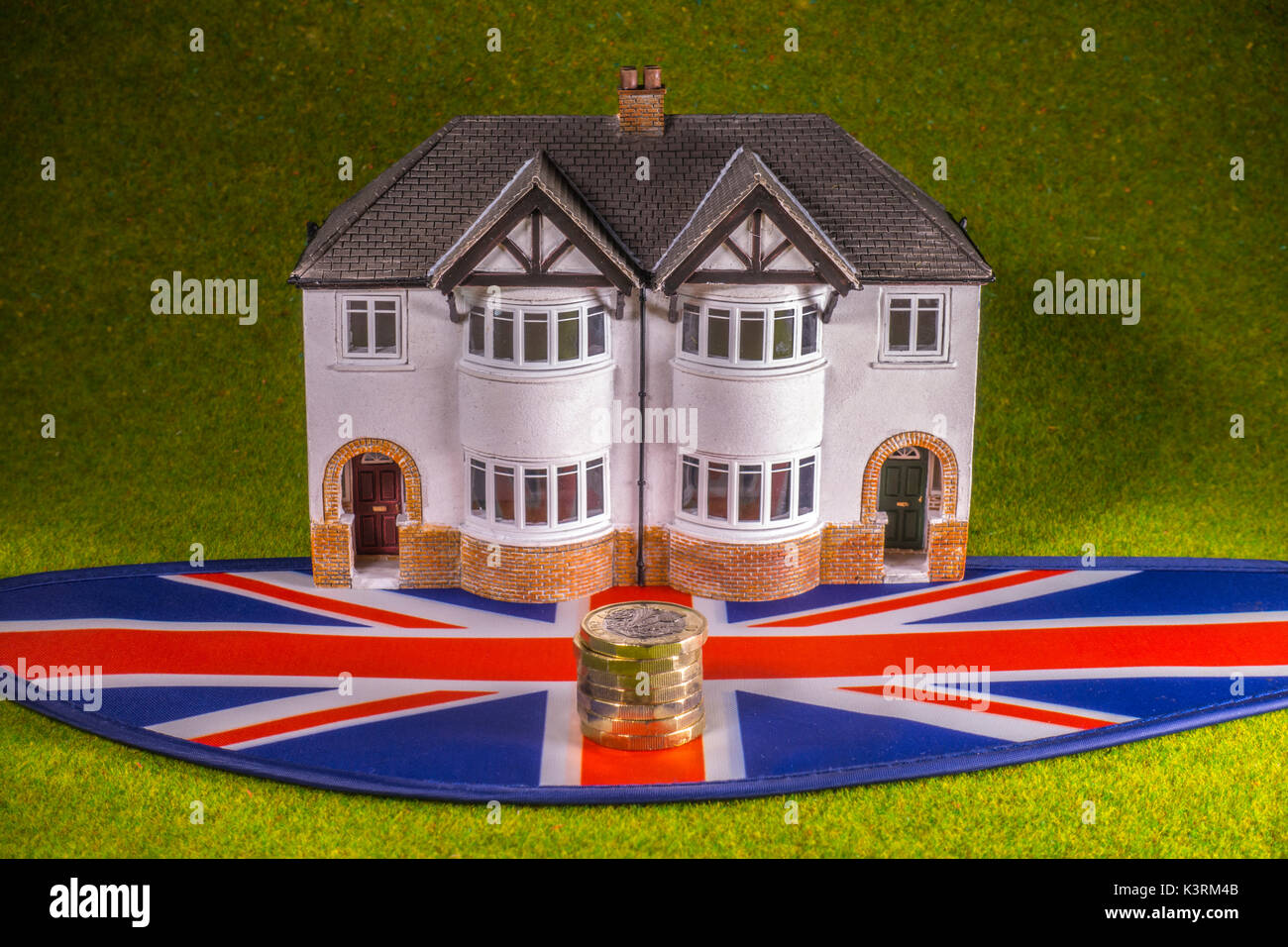 Model house, sterling pound coins (with new £1 coin) and Union Jack, to depict costs like a UK interest rate rise, home buying, renting, moving, etc. Stock Photo