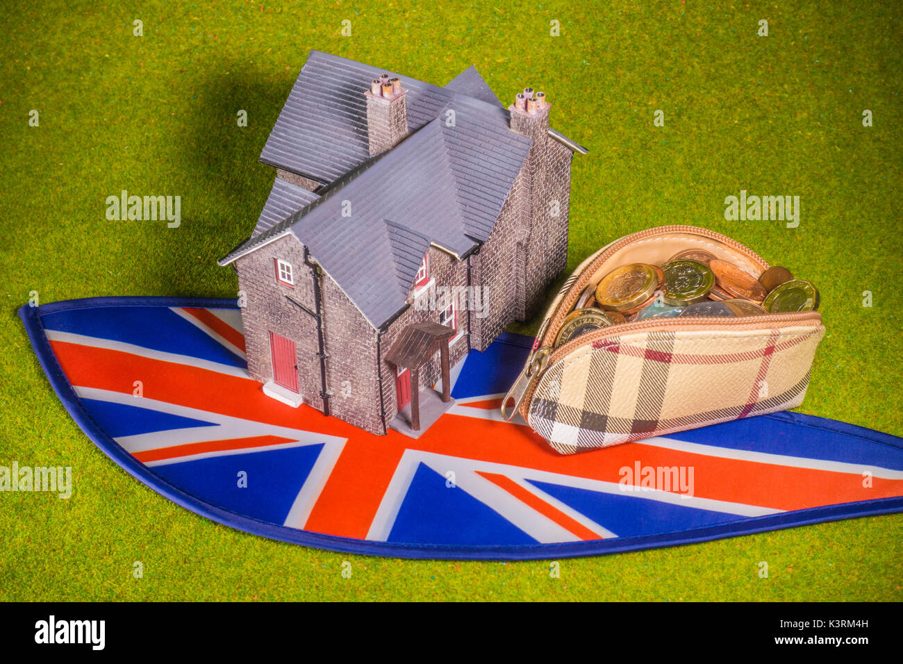 Model house, purse with sterling coins (with new £1) and Union Jack, to depict costs like a UK interest rate rise, home buying, renting, moving, etc. Stock Photo