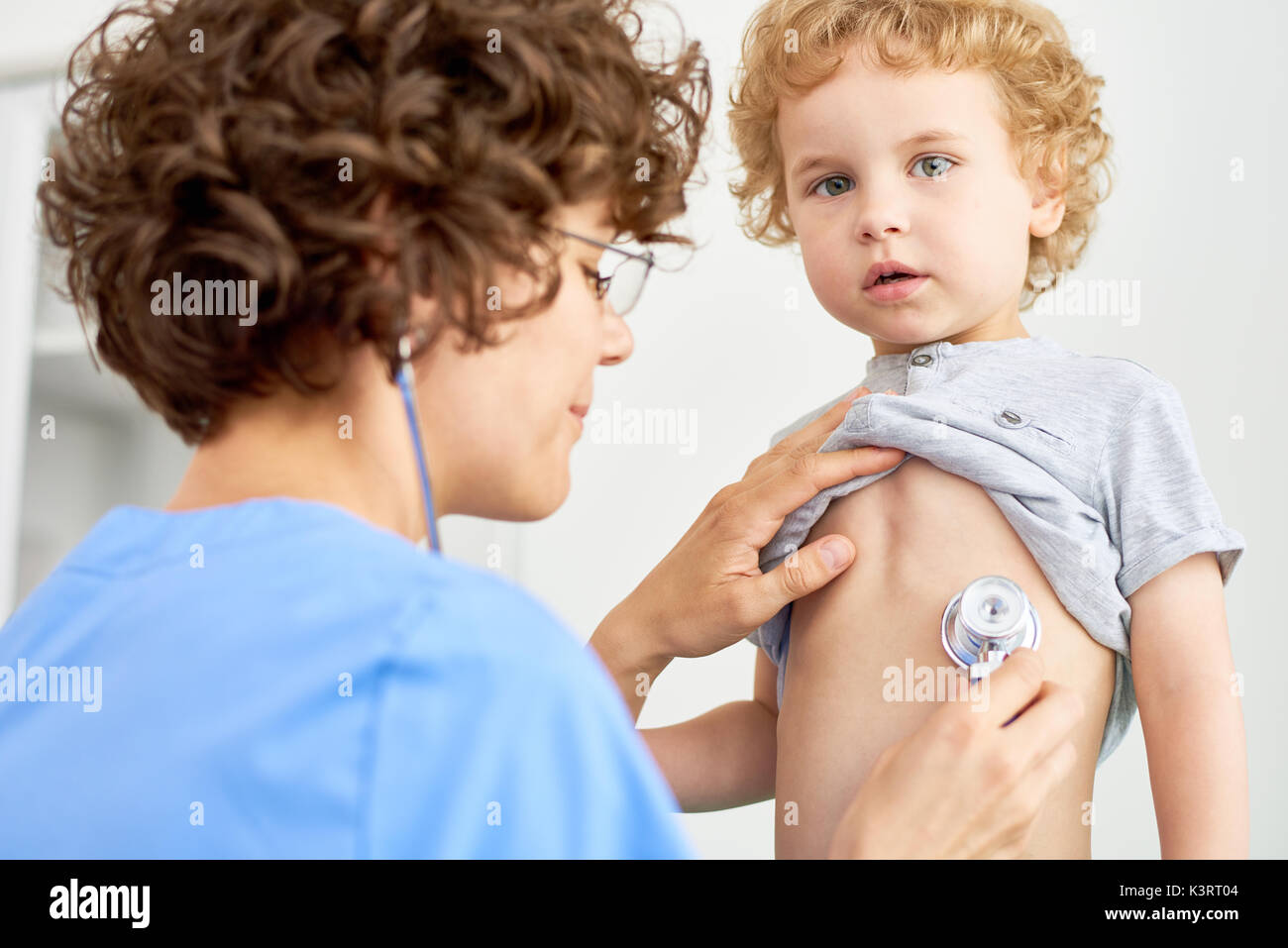 Portrait of female doctor listening to childs breathing using stethoscope Stock Photo