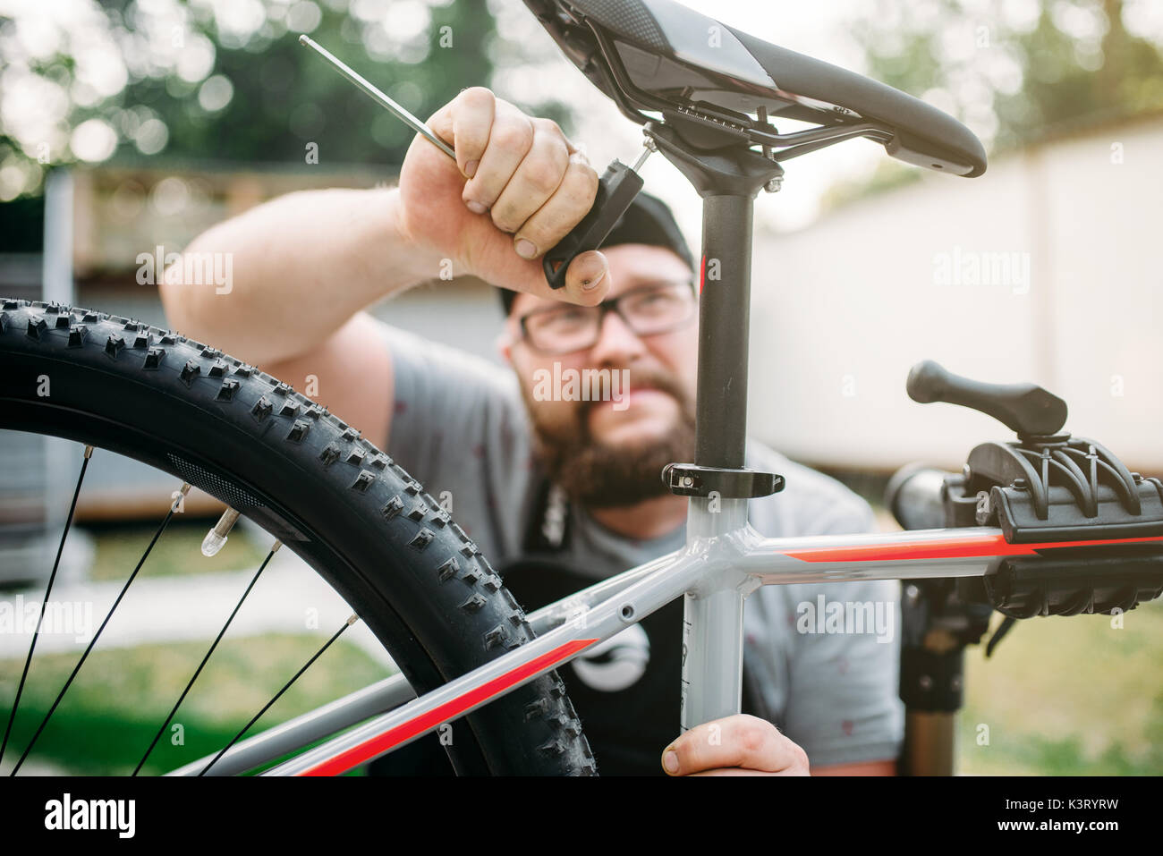 Bicycle mechanic adjusts with service tools bike seat. Cycle workshop outdoor. Bicycling sport, repairman at work Stock Photo