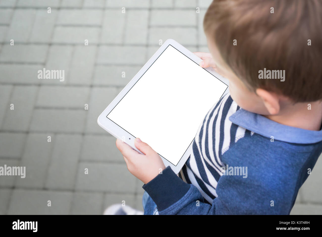 Boy holding tablet on city street. Device with isolated screen for mockup, template, product presentation. Stock Photo