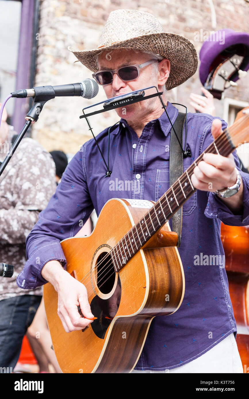 Skiffle group, High Chaparrals playing in the street. Close up of lead singer, wearing cowboy hat and acoustic playing guitar and blowing into harmonic. Stock Photo
