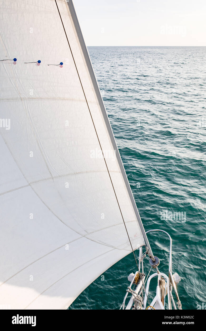 Sail, jib and turquoise ocean water in the background. Sailing boat