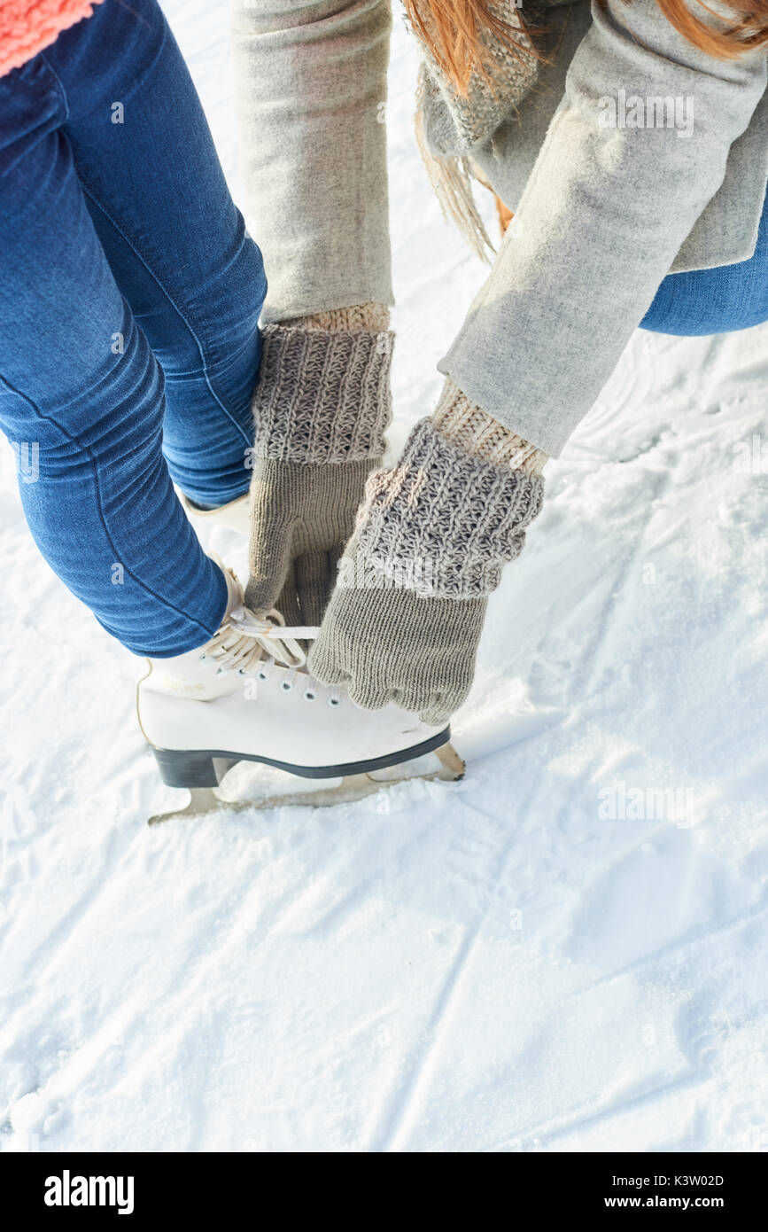 Mother binds shoes for daughter before going ice-skating Stock Photo