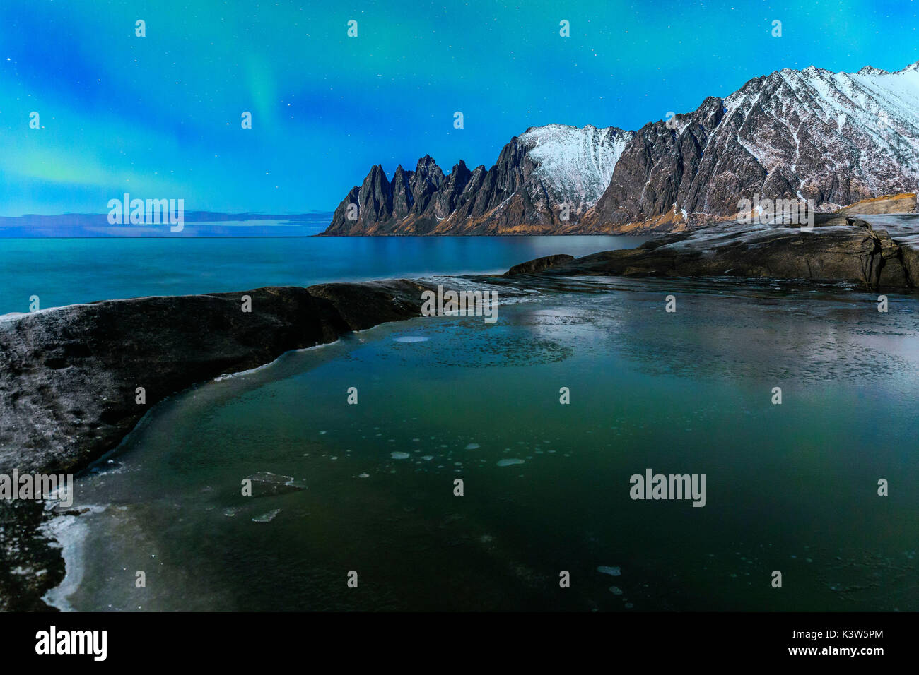 A weak nothern lights reflects in an icy puddle. Tungeneset, Ersfjorden, Senja, Norway, Europe. Stock Photo