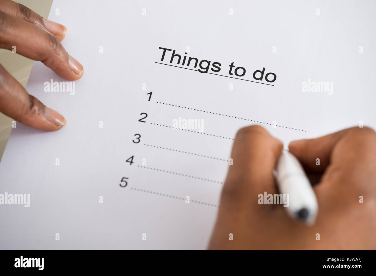 Close-up Of Person's Hand Writing Things To Do List On Paper Stock Photo