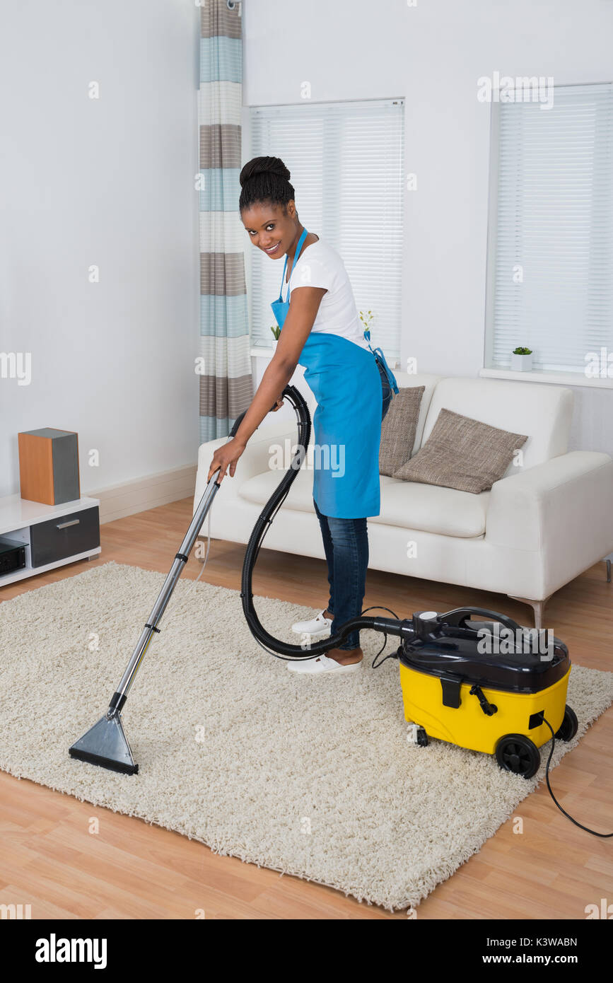 Smiling Young African Woman Cleaning Carpet With Vacuum Cleaner Stock Photo Alamy