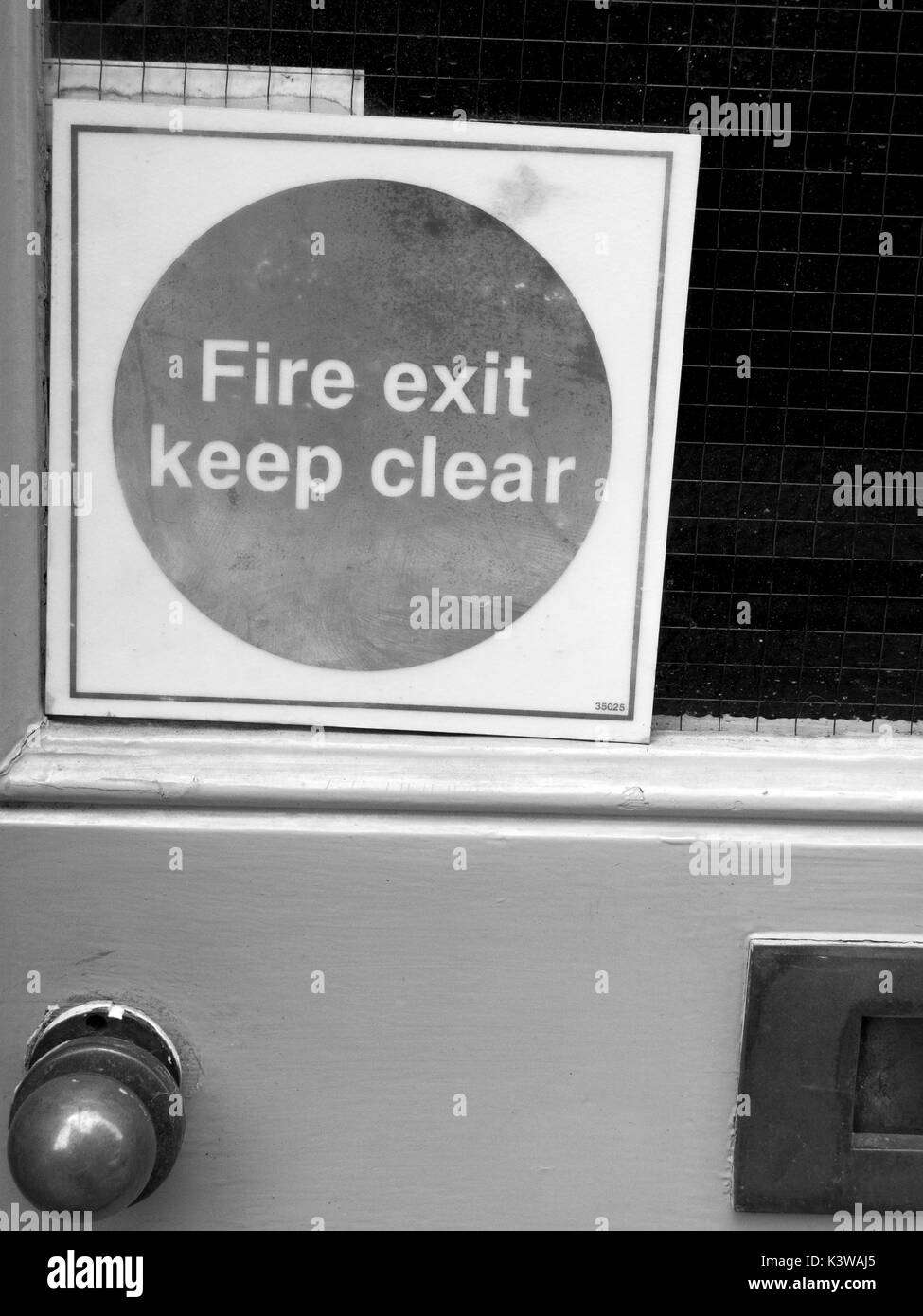 Fire exit keep clear mandatory self adhesive sticker on rear entrance door to retail unit Stock Photo