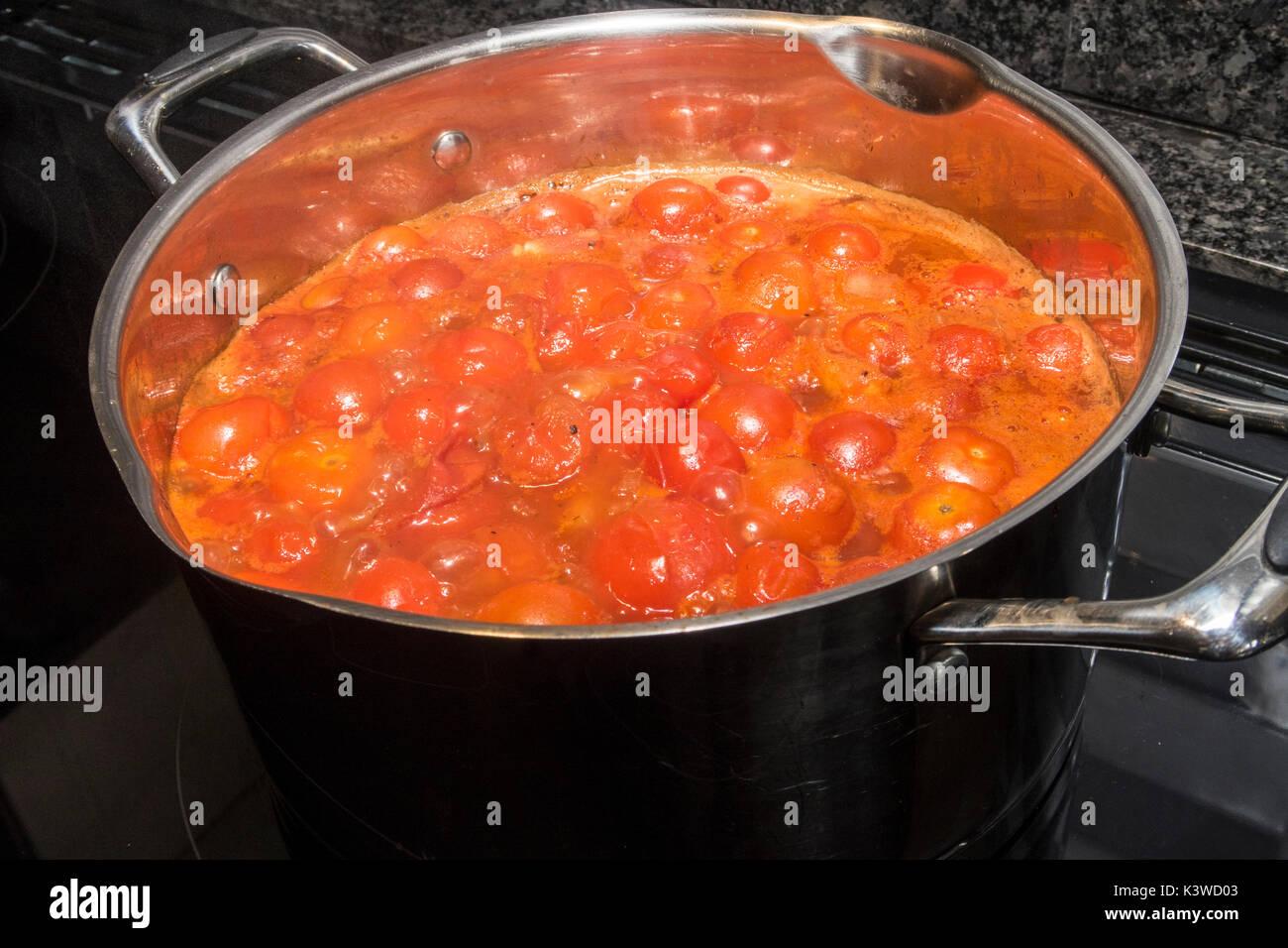 Making tomato soup in a stainless steel pan on an induction hob. Stock Photo