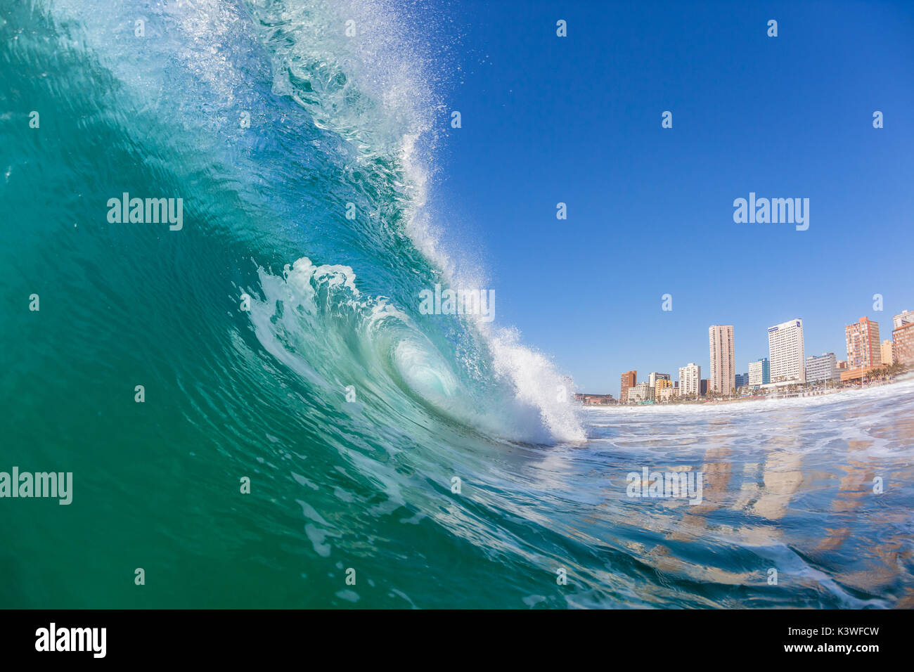 Ocean wave power surfing surfer view inside out hollow crashing tube along Durban beachfront. Stock Photo