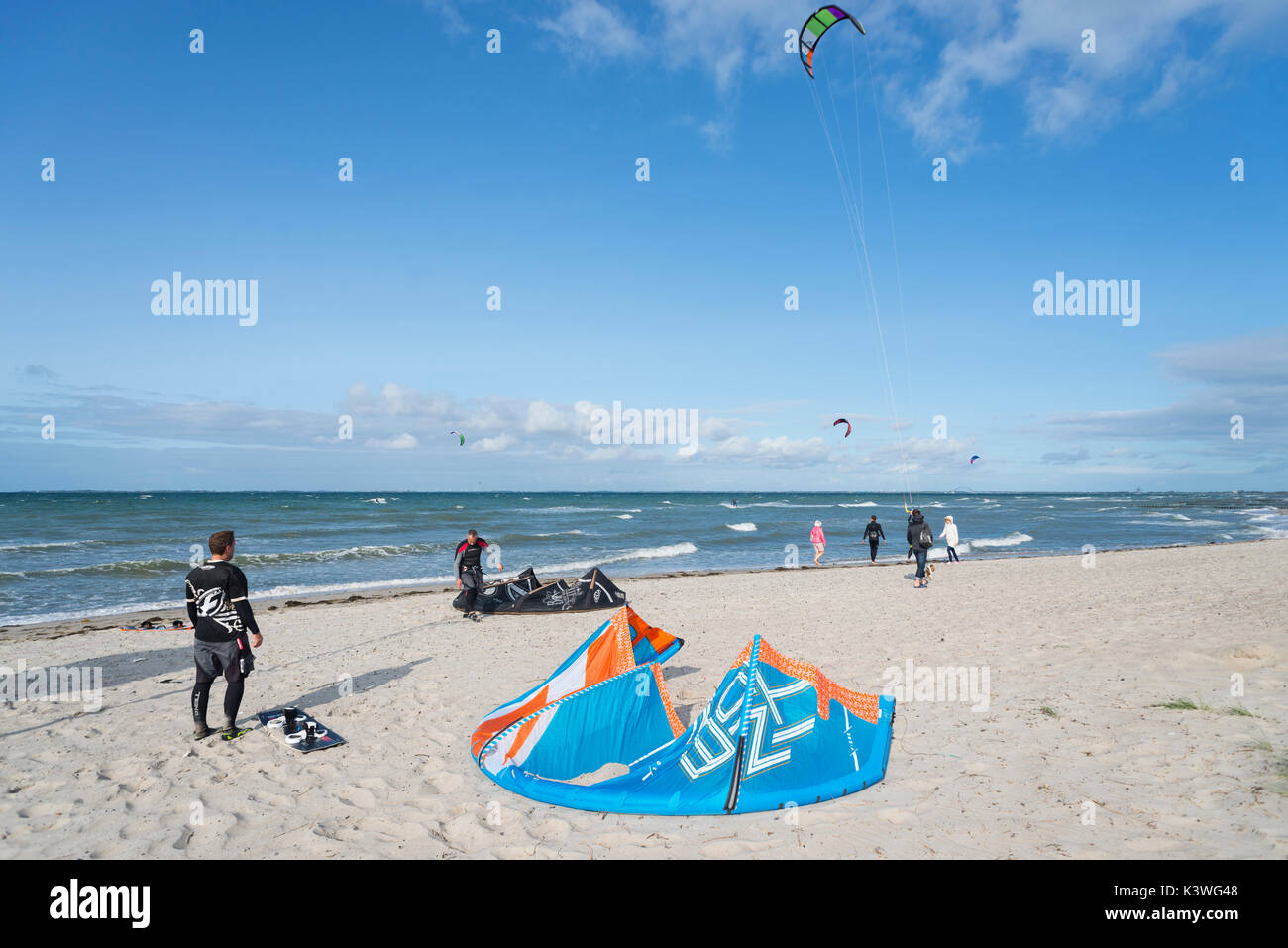 Kite surfer preparing at the beach and surfing on the sea at the Steinwarder beach at Heiligenhafen, Schleswig-Holstein, Germany Stock Photo
