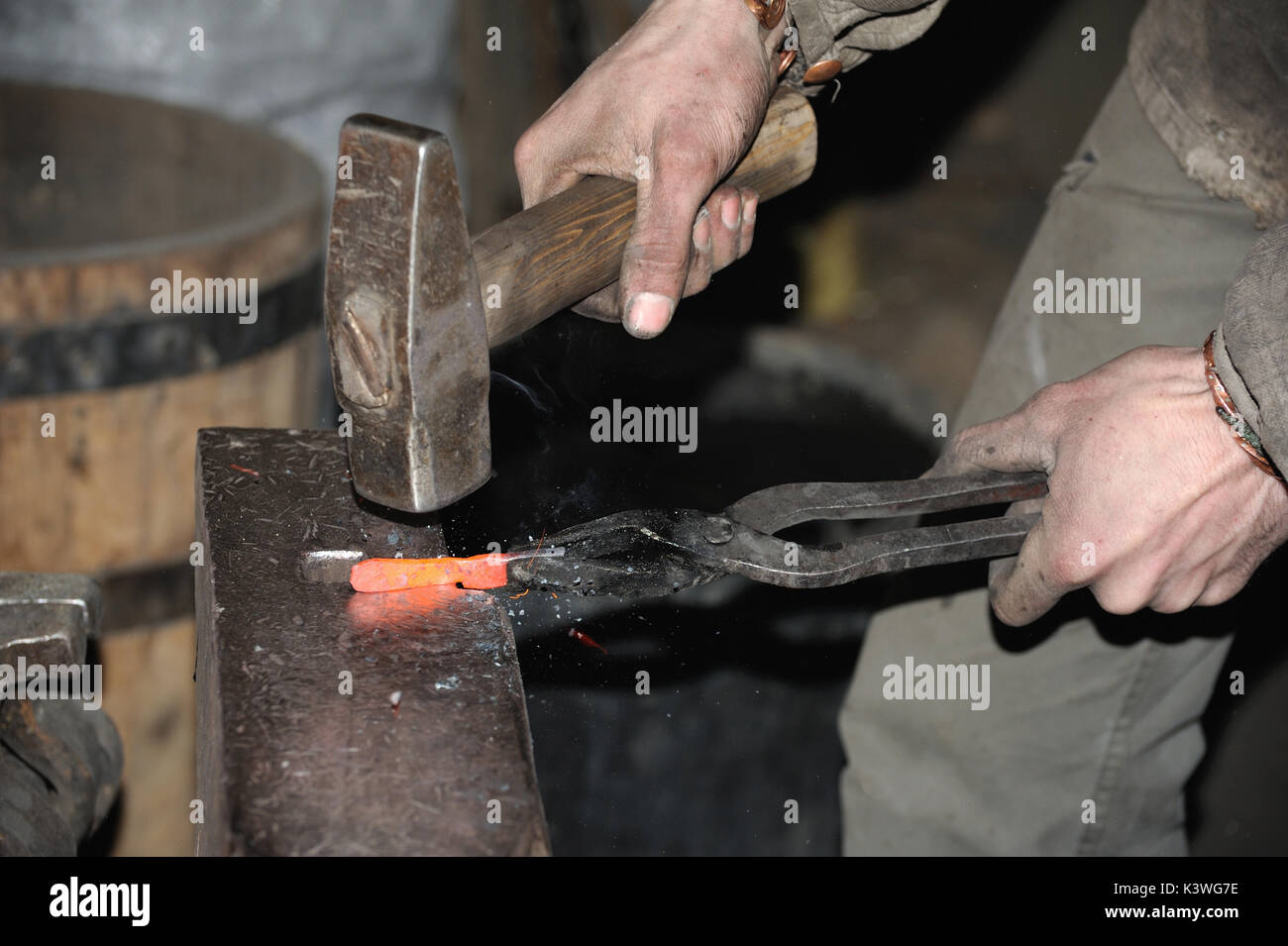 Blacksmith working metal with hammer on the anvil in the Stock