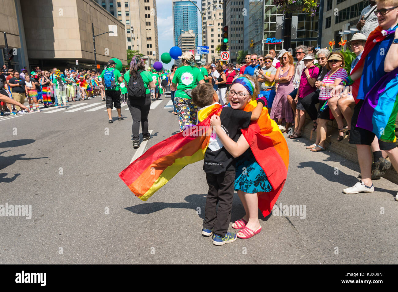 Montreal, CANADA - 20 August 2017: Ayoung boy wearing a rainbow cloat is hugging a young woman at Montreal Gay Pride Parade - Free Hugs Stock Photo